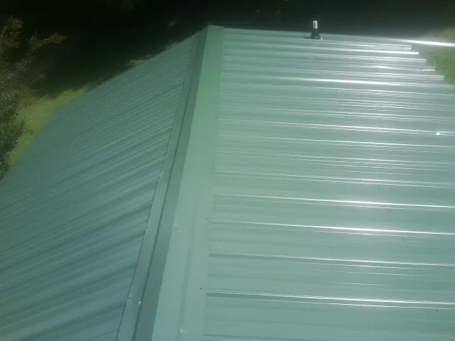 New green metal panels meeting at the ridge of a roof in Sparta